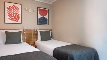 Een hotelkamer met twee bedden, een houten hoofdbord en kunst aan de muur.