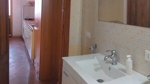 Une cuisine avec des meubles de rangement en bois, un plan de travail blanc et un évier.