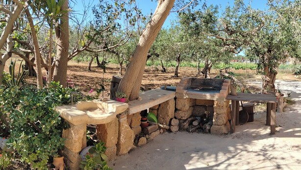 Un espace barbecue extérieur doté d’un grill en pierre et de sièges.