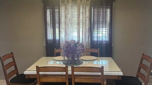 Un comedor con una mesa rectangular, seis sillas de madera, una araña y un centro de mesa con flores.