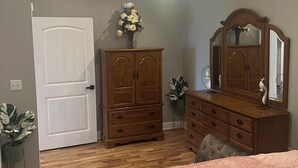 Un dormitorio con cama, cómoda, espejo, ventilador de techo y puerta.