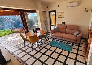 Una sala de estar con sofá, sillones, una mesa y vistas al exterior.