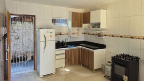 A kitchen with white cabinets, a black countertop, a refrigerator, and a stove. - Beach house in Itamaraca (Jaguaribe Ilha de Itamaracá)