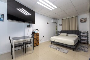 Un dormitorio con cama, escritorio y televisor.
