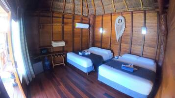 Une cabane en bois avec deux lits, une petite table et un toit de chaume.
