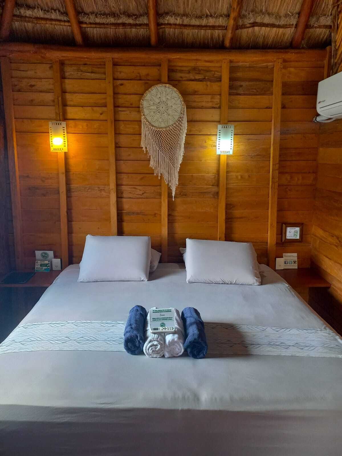 Une pièce de style cabane en bois, comprenant un lit, deux oreillers, une décoration murale et deux lampes fixées au mur.
