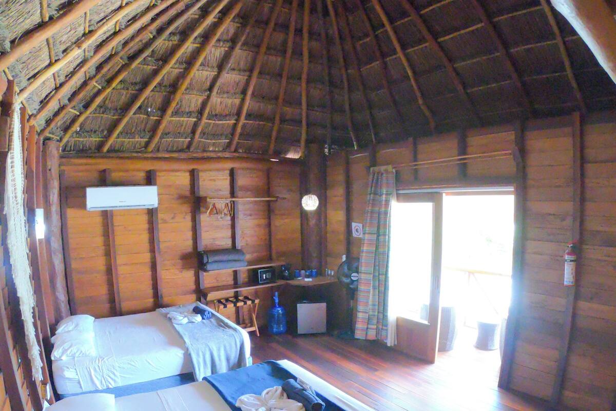 A room with two beds, a desk, and a kitchenette.
