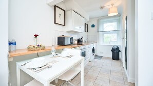 Eine moderne Küche mit weißen Schränken, einer Holzarbeitsplatte und einem Essbereich mit einem weißen Tisch.