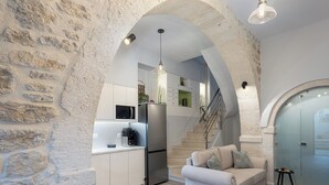 A modern kitchen with white cabinets, a built-in microwave, and a coffee machine.