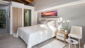 A modern bedroom with a large bed, a bedside table with a vase of flowers, and a chair.