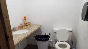 A small bathroom with a sink, toilet, and trash bin. - La Poza, El Yunque!!! Camping Area 1 (Palmer)
