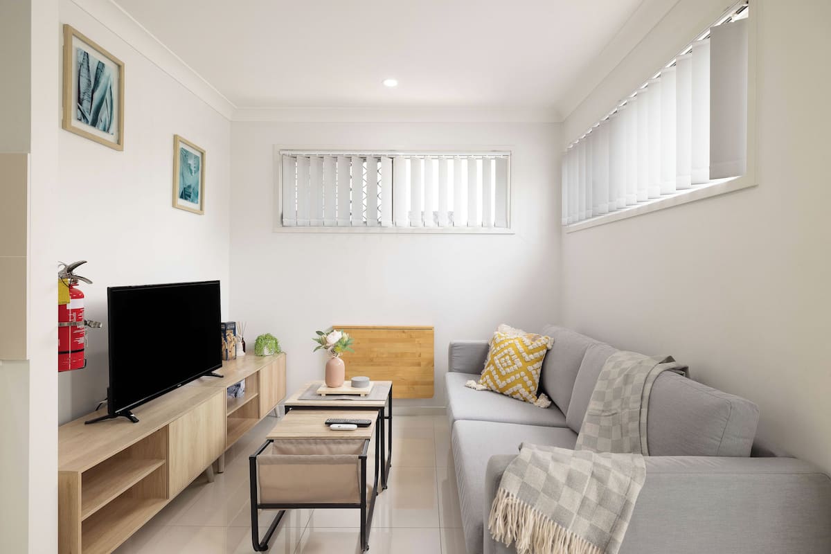 A modern living room with a flat-screen TV, a sofa, a coffee table, and a small side table.