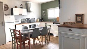 A modern kitchen with a dining area, white cabinets, a microwave, and a sink. - Charming new 70 m² house in the heart of the Pines (L'Aiguillon-la-Presqu'île)