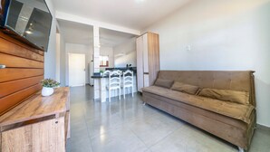 Una sala de estar con un sofá marrón, una mesa de madera y un televisor instalado en la pared.