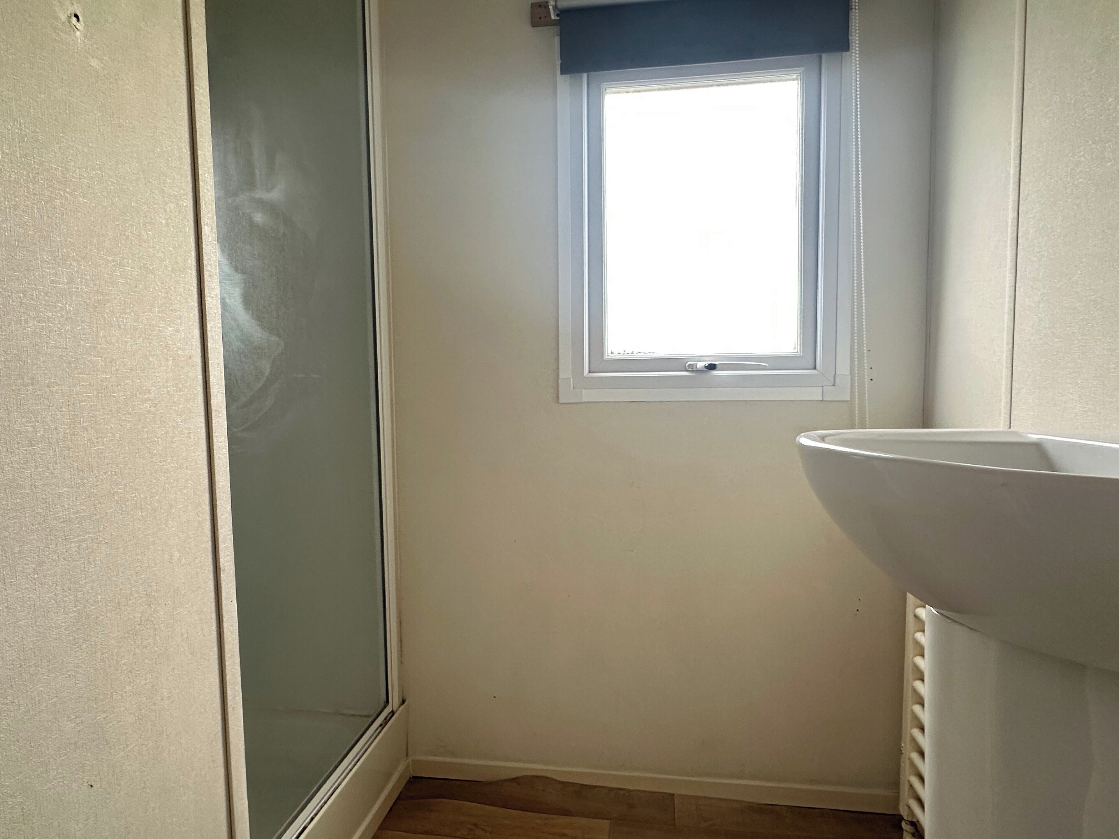 Ein Blick in den Raum, mit Fenster, Heizkörper und Tür.