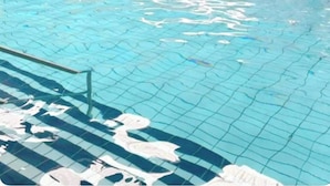 An indoor swimming pool with clear blue water, tiled walls in yellow and blue, and a visible pool ladder. - Harwich - Caravan - Sleeps 10 - Garden - Pool (Harwich)
