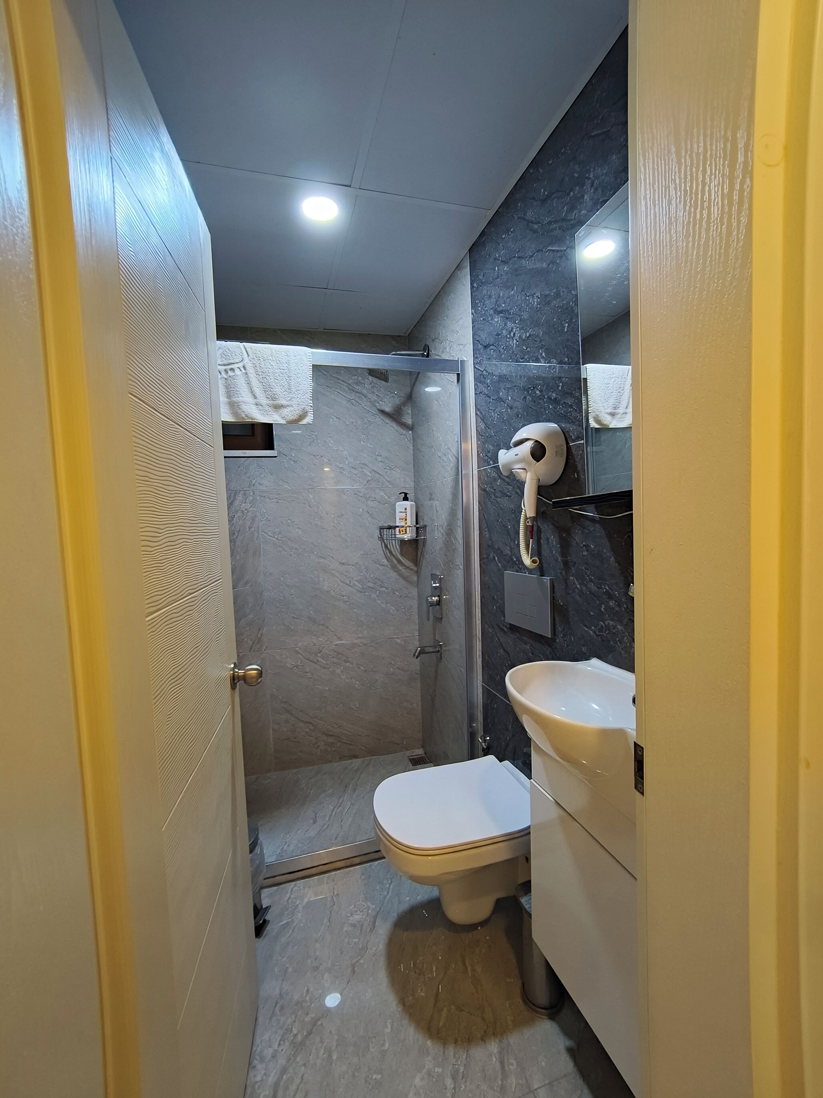 Un baño pequeño con ducha, inodoro y lavamanos.