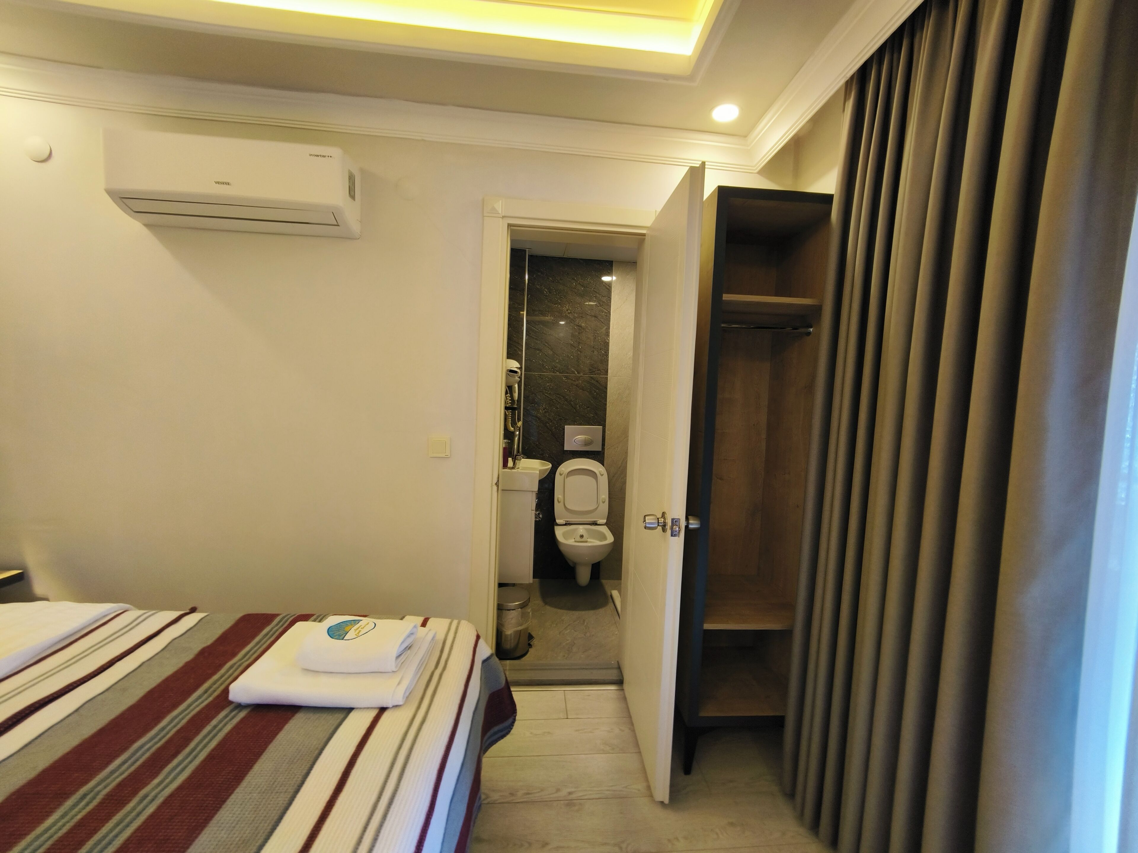 Habitación de hotel con cama, baño con inodoro y zona de ducha.