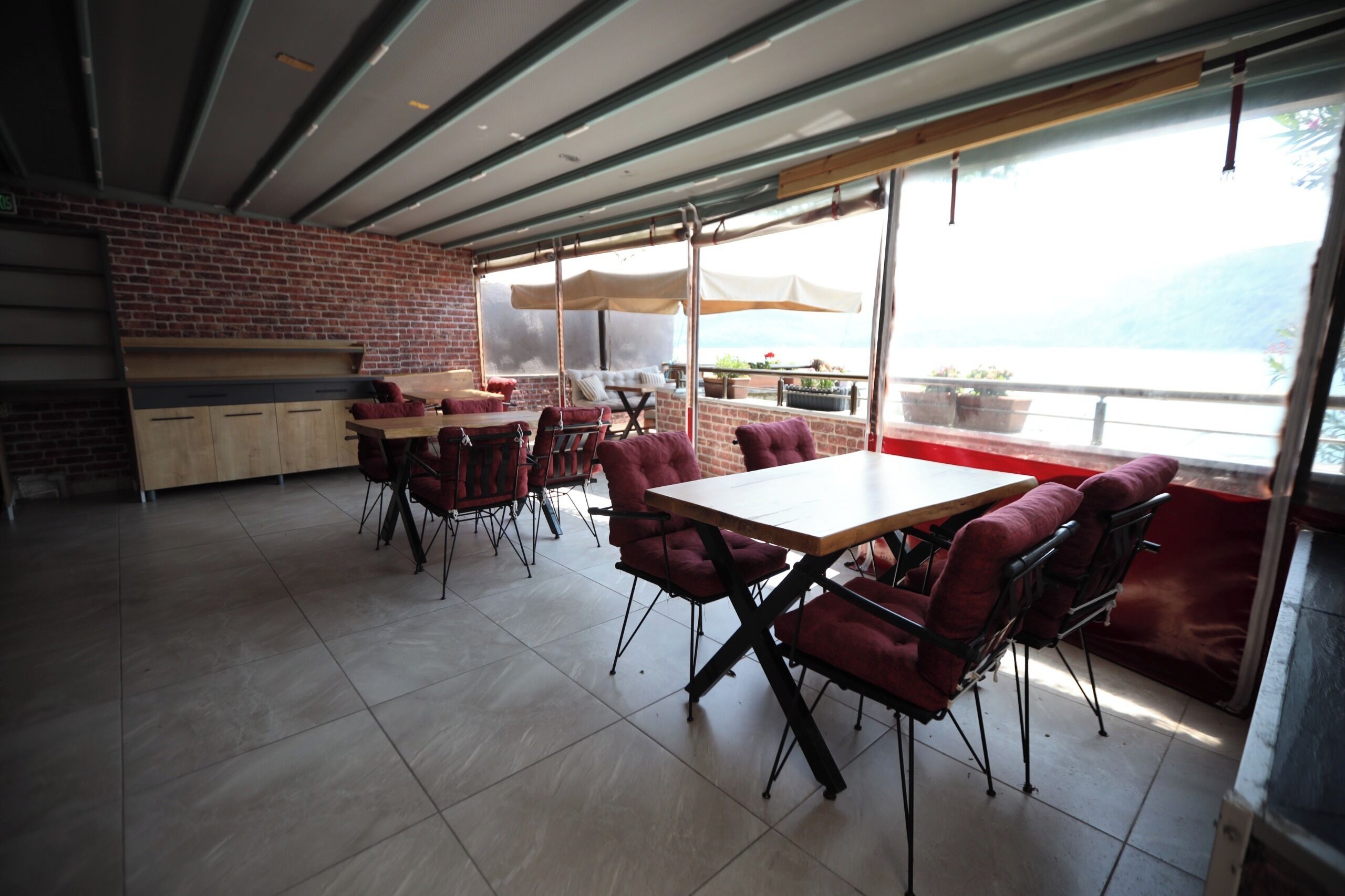 Comedor de planta abierta con pared de ladrillo, ventanas amplias y vista al agua.