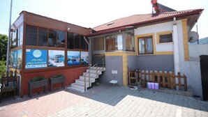 A two-story building with a glass front, a staircase, and a wooden fence. - AMASRA EMEK PANSİYON (Amasra)
