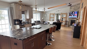 Een ruime keuken met een groot eiland, houten kastjes en moderne hanglampen.