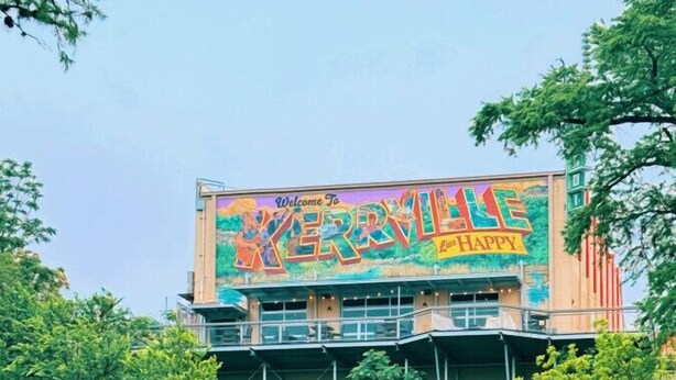 Ein Gebäude mit einem farbenfrohen Wandgemälde, das „Willkommen in KERRVILLE“ und „Live the HAPPY“ zeigt.