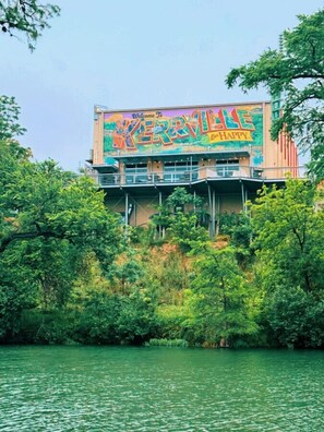 Een gebouw met een kleurrijke muurschildering waarop staat: 'Welkom in KERRVILLE' en 'Leef GELUKKIG'.