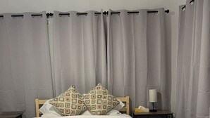 A neatly made bed with an orange blanket, two patterned pillows, and a bedside table with a lamp.