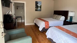 Habitación de hotel con dos camas, un escritorio, una silla y un televisor.