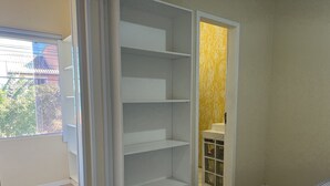 Un dormitorio con armario empotrado, ventana y baño con pared amarilla.