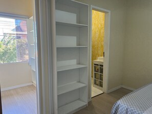 Une chambre avec un placard intégré, une fenêtre et une salle de bain avec un mur jaune.