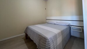 Un dormitorio pequeño y ordenado con una cama individual, una mesita de noche y un estante en la pared.