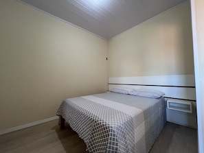 Un dormitorio pequeño y ordenado con una cama individual, una mesita de noche y un estante en la pared.