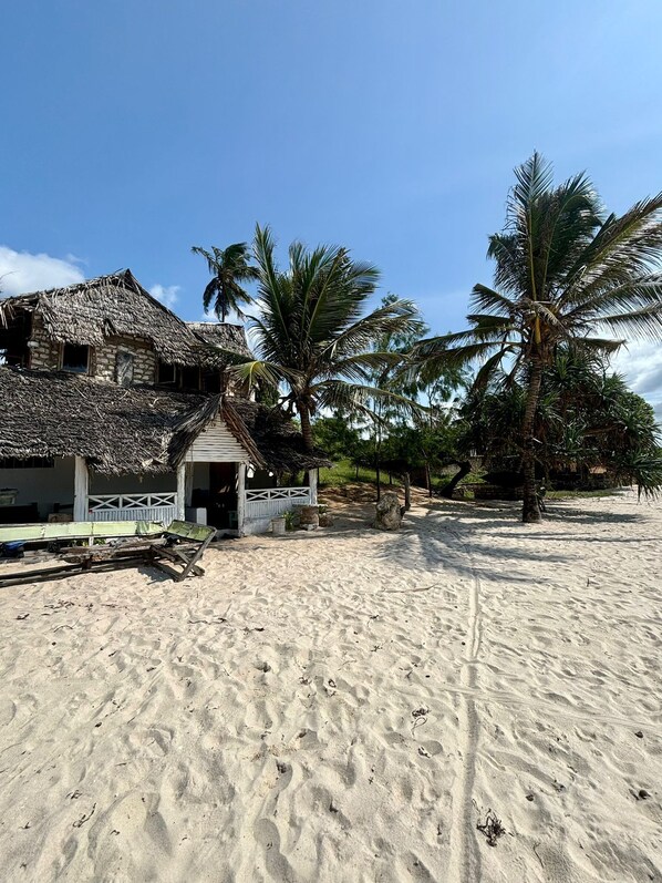 A beach house with a thatched roof and a small porch. - Charming beach-front cottage in Tiwi for easy-going friends with AC and WiFi (Tiwi)
