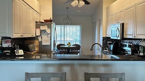 A modern kitchen with white cabinets, a central island with a sink, and a dining area with a table and chairs.