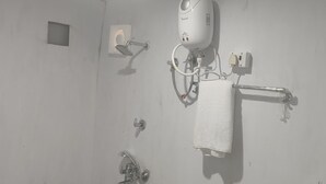 A bathroom with a toilet, a bidet, a towel rack, and a hand dryer. - Maha Kumbh Mandapam  (Karchana)