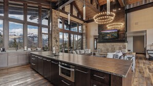 A spacious kitchen with a large island, stone walls, and a view of mountains. - Telluride Ridge / Hot Tub, Fire Pit & Mountain Views (Mountain Village)