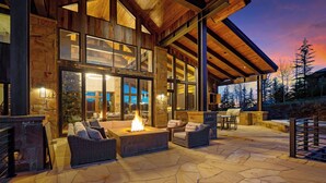 A stone patio with a fire pit, wicker furniture, and a stone fireplace. - Telluride Ridge / Hot Tub, Fire Pit & Mountain Views (Mountain Village)