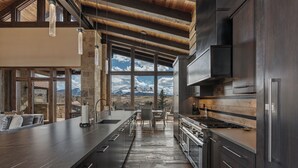 Una cocina moderna con una isla grande, electrodomésticos de acero inoxidable y vistas a las montañas a través de amplios ventanales.