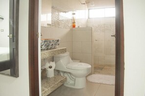 Une salle de bain comprenant des toilettes, un lavabo et un espace douche.