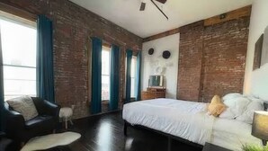 Ein modernes Schlafzimmer mit einem großen Bett, einer schwarzen Ledersofa und einem kleinen Hund.