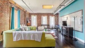 Ein Wohnzimmer mit einem gelben Sofa, einem Couchtisch und einer Ziegelwand.