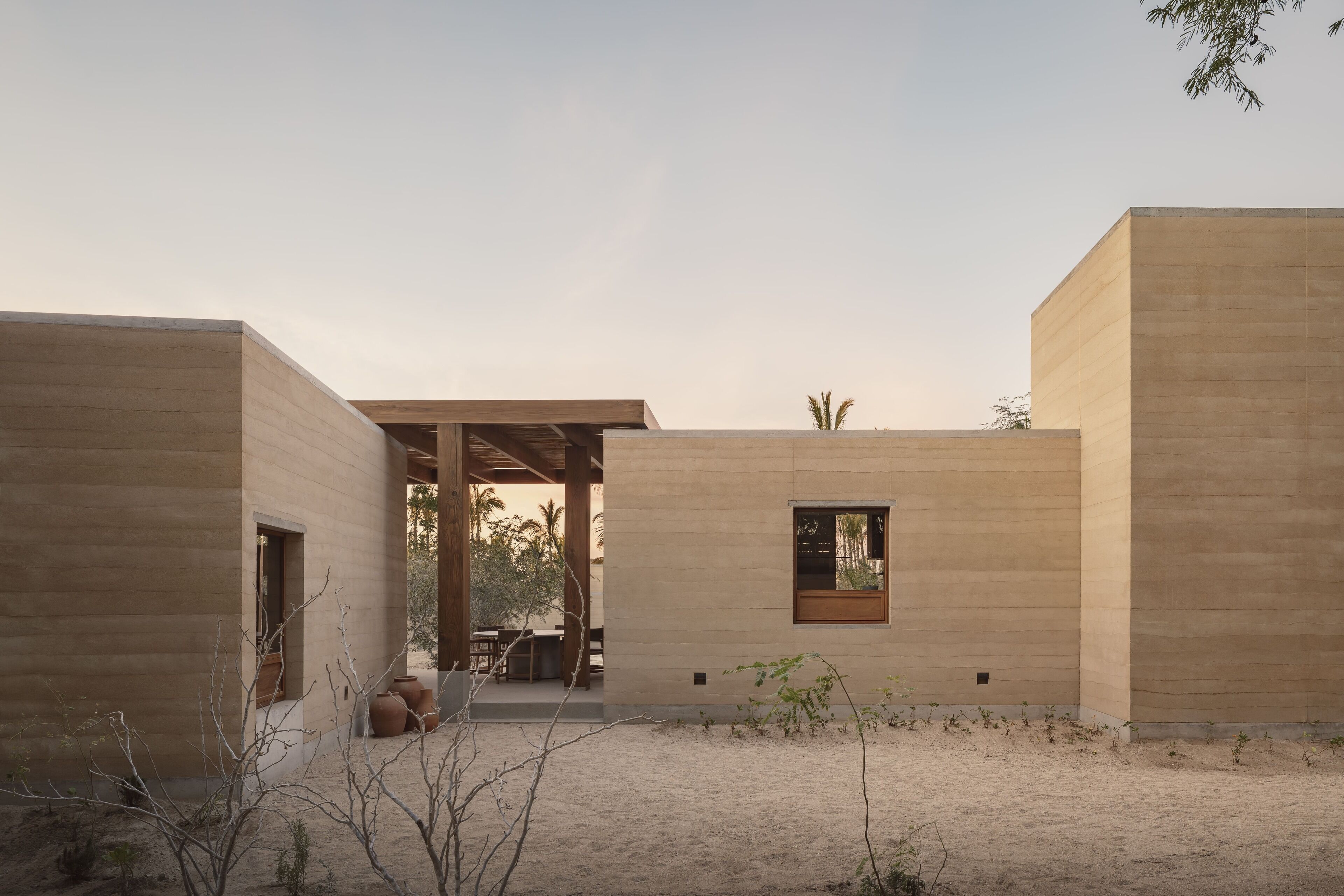 Ein modernes Gebäude mit minimalistischem Design, das einen überdachten Außenbereich mit Tisch und Stühlen bietet.
