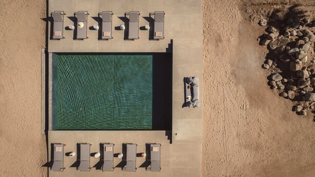 An aerial view of a pool area with sun loungers arranged around it, a clear pool, and a rocky landscape to the right. - Salara Boutique Hotel & Villas Todos Santos (El Pescadero)