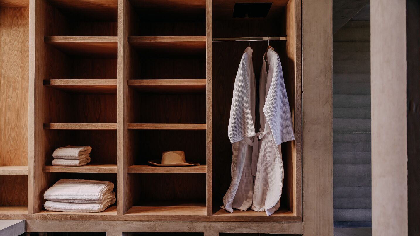 A wooden wardrobe with multiple shelves, a hanging rack, and folded towels.