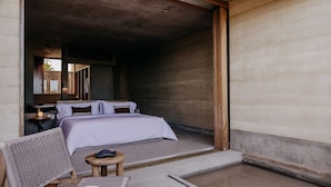 Une chambre à coucher avec un lit, une chaise, une petite table et une porte en bois.