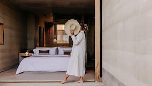 Une chambre avec un lit, une table de chevet et une grande fenêtre.