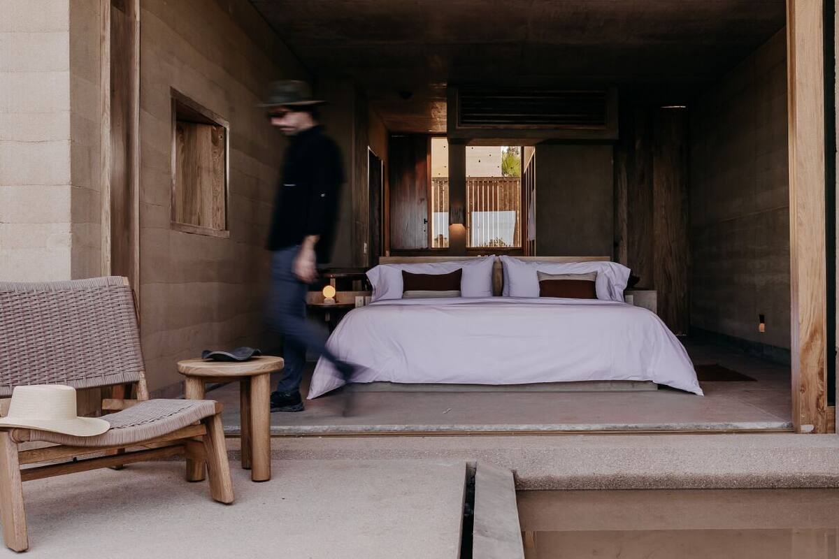 A room with a bed, a small table, a chair, and a window.