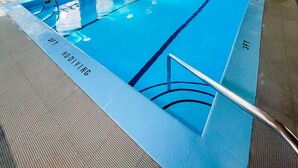 An indoor swimming pool with wooden ceiling and walls, clear lane markings, and a lifeguard chair.
