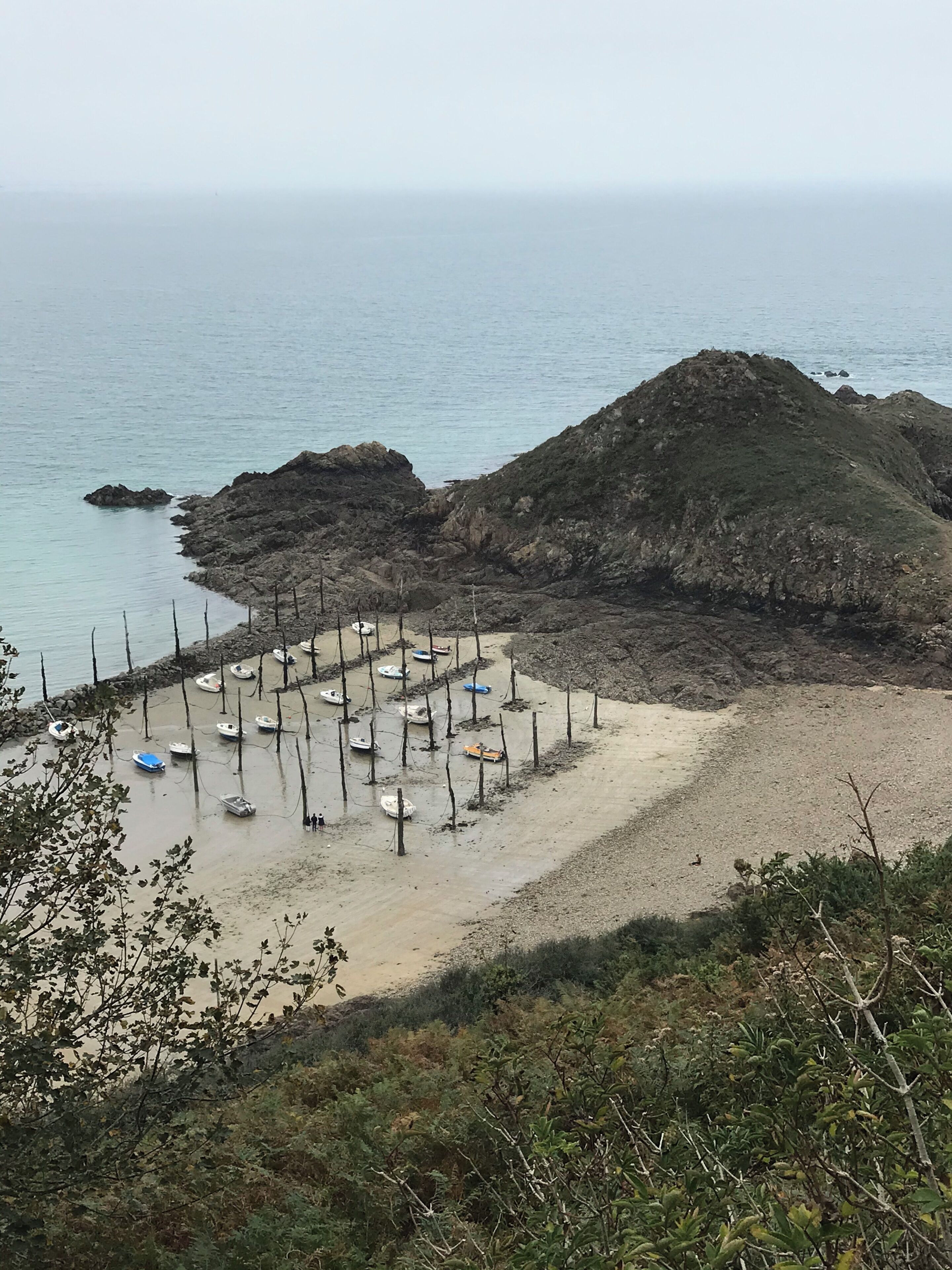A beach with boats and a rocky hill.